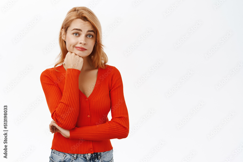 Image of young woman in red blouse, looking thoughtful, thinking of solution, pondering smth, standing over white background Image of young woman in red blouse, looking thoughtful, thinking of solution, pondering smth, standing over white background