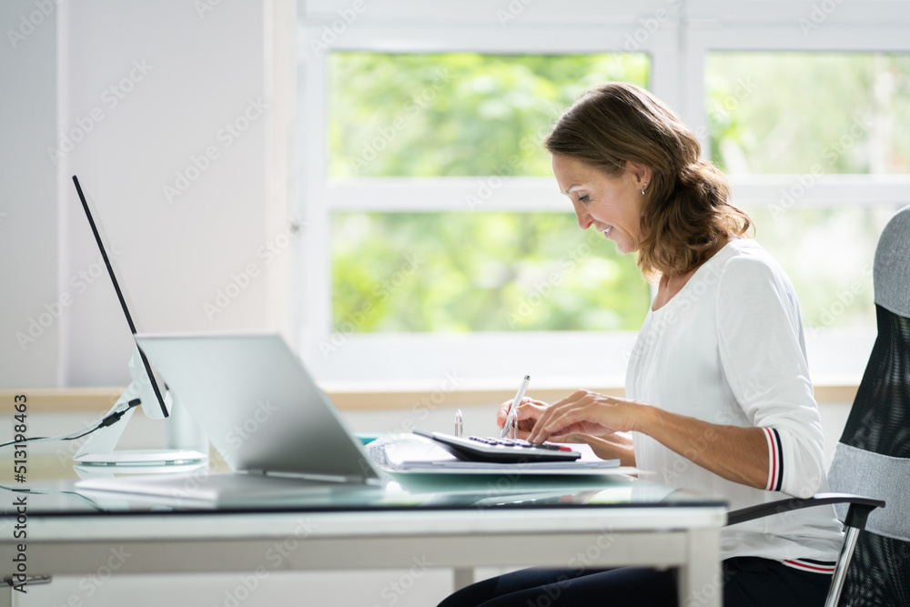 Young Businesswoman Calculating Bill In Office Young Businesswoman Calculating Bill In Office