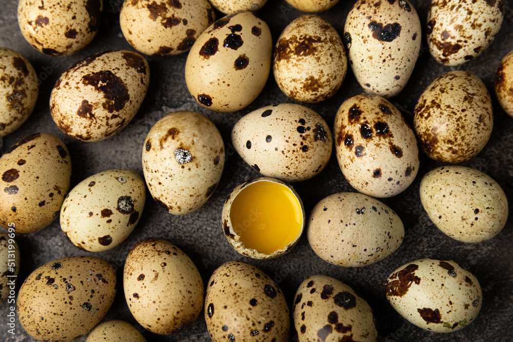 Quail eggs on a black texture background. Whole and broken quail eggs. Natural products. Place for text. Fresh quail eggs.