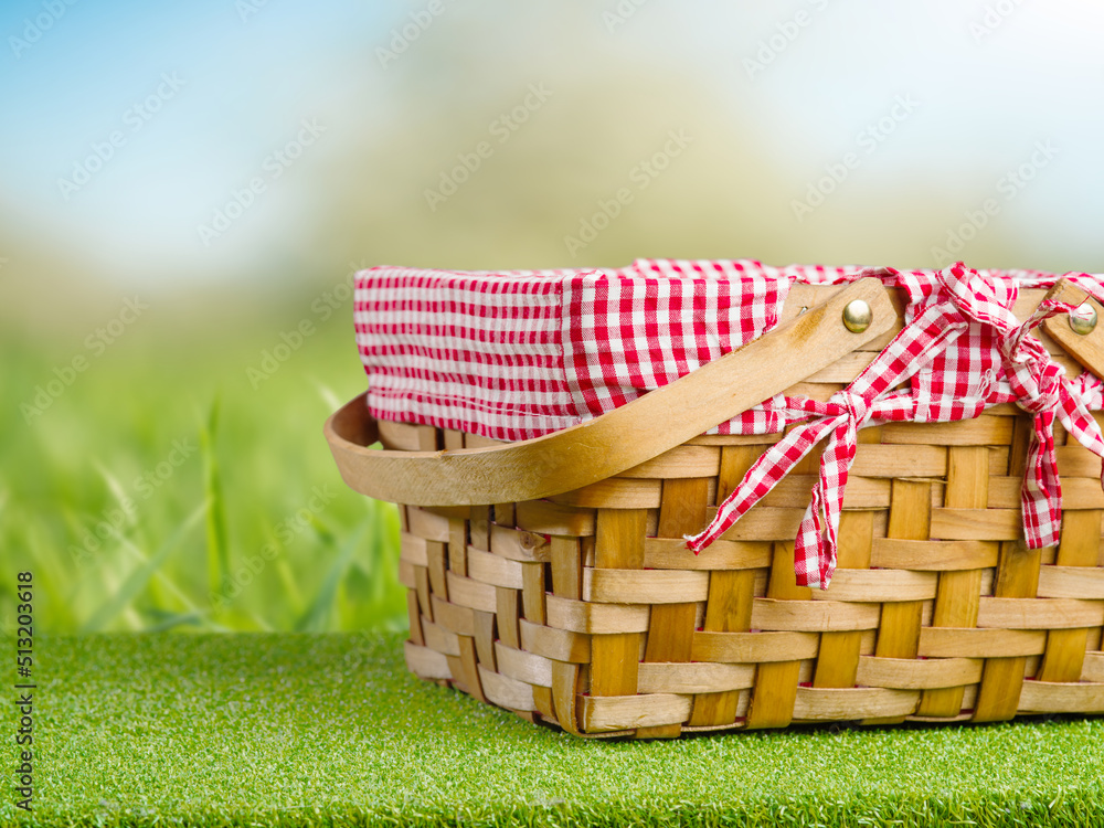 Obraz premium A beautiful picnic basket on a bright green grass against the backdrop of nature. Summer vacation, picnic. Beautiful nature, delicious organic food. Banner, advertisement, invitation.