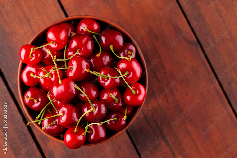 Ripe cherries in a clay bowl. Red cherries on a wooden table. Healthy vegan food concept. Top view. Copy space Ripe cherries in a clay bowl. Red cherries on a wooden table. Healthy vegan food concept. Top view. Copy space