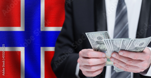 Hands holding dollar money on flag of Norway
