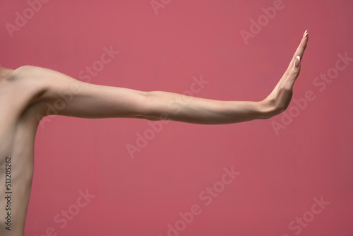 Young woman's stretched skinny arm with stop gesture. Isolated on pink background © vladimirfloyd