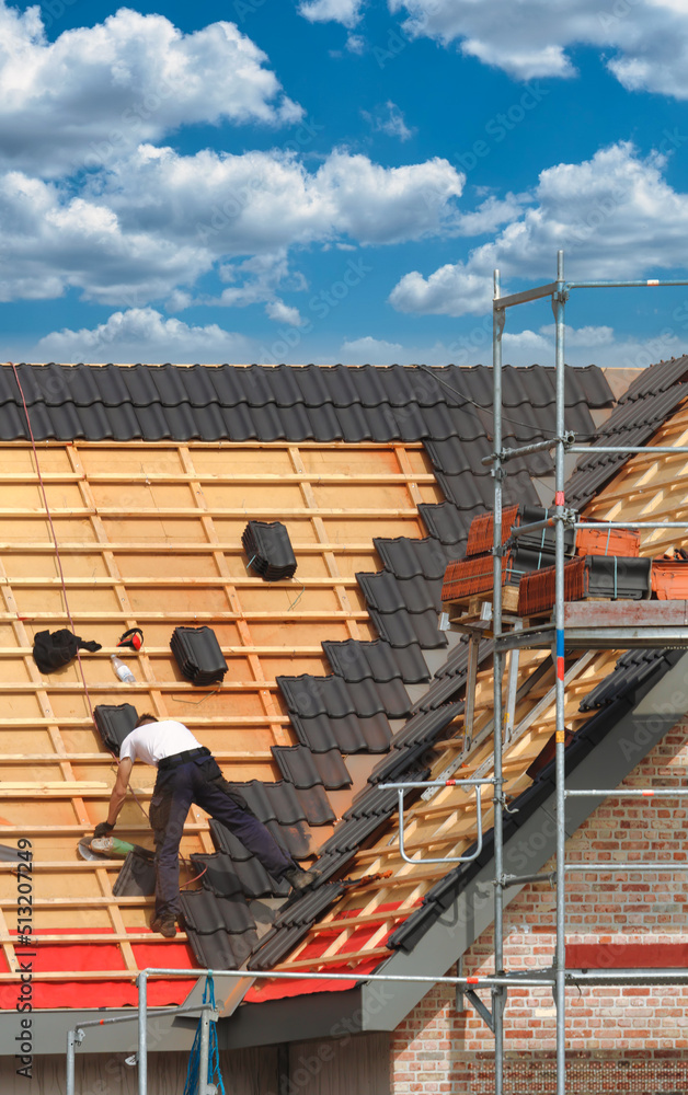 Bauarbeiten / Dachdeckerarbeiten: Dachdecker deckt Steildach eines eingerüsteten Neubaus / Rohbaus ein Bauarbeiten / Dachdeckerarbeiten: Dachdecker deckt Steildach eines eingerüsteten Neubaus / Rohbaus ein