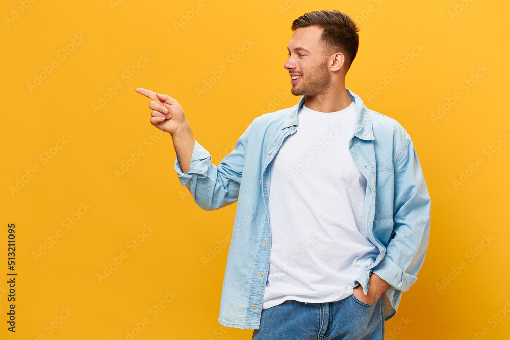Happy cheerful tanned handsome man in blue basic t-shirt point finger look aside posing isolated on orange yellow studio background. Copy space Banner Mockup. People emotions Lifestyle concept Happy cheerful tanned handsome man in blue basic t-shirt point finger look aside posing isolated on orange yellow studio background. Copy space Banner Mockup. People emotions Lifestyle concept