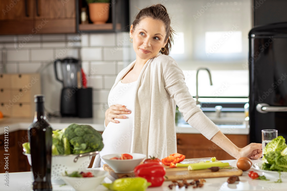 Pregnant woman in the kitchen prepare healthy vegetarian food  and smile