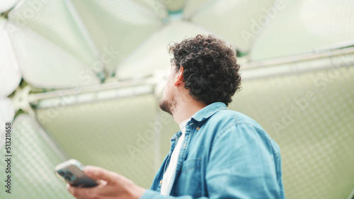 Close-up, man looks at google map on mobile phone and looks around on modern city background