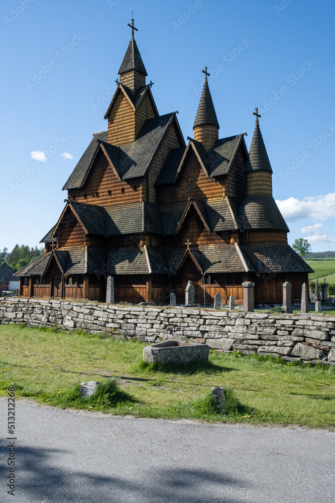 Heddal, Norway - May 26, 2022: Medieval graveyard and Heddal wooden stave church. Heddal Stavkirke, 13th century. Largest stave church in Norway. Sunny spring day.  Selective focus