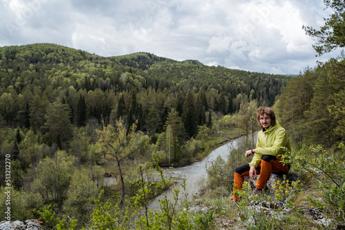 Summer vacation in nature, domestic tourism, traveling to his native land, Russia South Urals, a guy sitting on a stone in the forest, hiking.