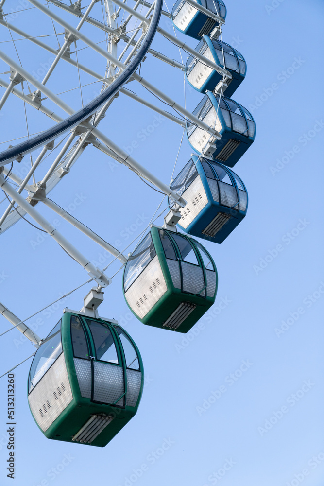 Closeup of colorful cabins of giant ferris wheel in amusement park against blue sky. Tbilisi, Georgia. Entertainment concept - obrazy, fototapety, plakaty 