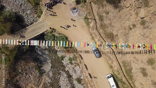 aerial drone view looking down a suspension bridge with people walking on the colored steps over a river in Cumbe, San Mateo de Otao in the day in a bird's eye view 4k photo