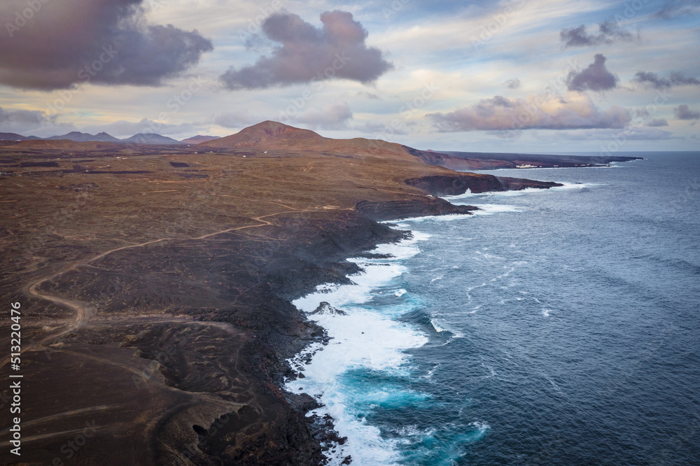 aerial view on volcano and mountains on coast with ocean waves on lanzarote