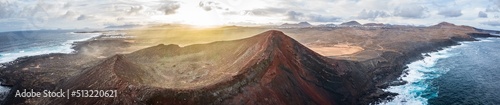 aerial panorama view on volcano and mountains on coast with ocean waves on lanzarote during sunrise