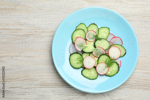 Tasty salad with cucumber and radish on wooden table, top view. Space for text