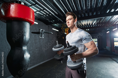 Determined muscular man exercising with hand weights