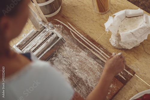 Wallpaper Mural A woman slices noodles with a noodle cutter against the background of a wooden kitchen board Torontodigital.ca