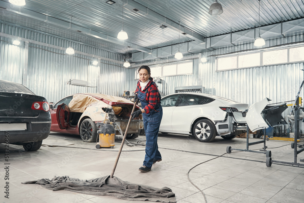 Attentive female person cleaning territory of workshop Attentive female person cleaning territory of workshop