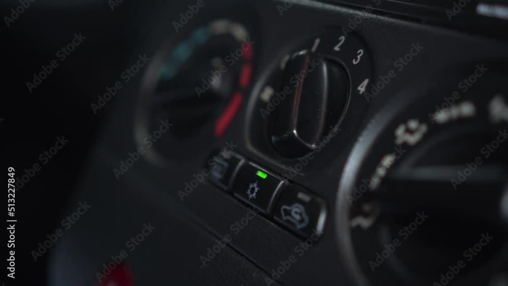 The woman presses the air conditioner button in the car. Automotive panel close-up. The woman presses the air conditioner button in the car. Automotive panel close-up.