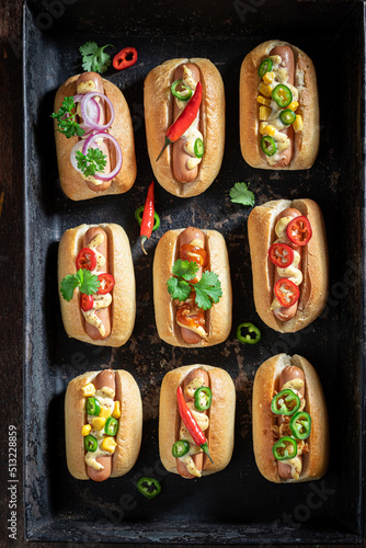 Unhealthy and tasty mini hot dogs with mustard and herbs.