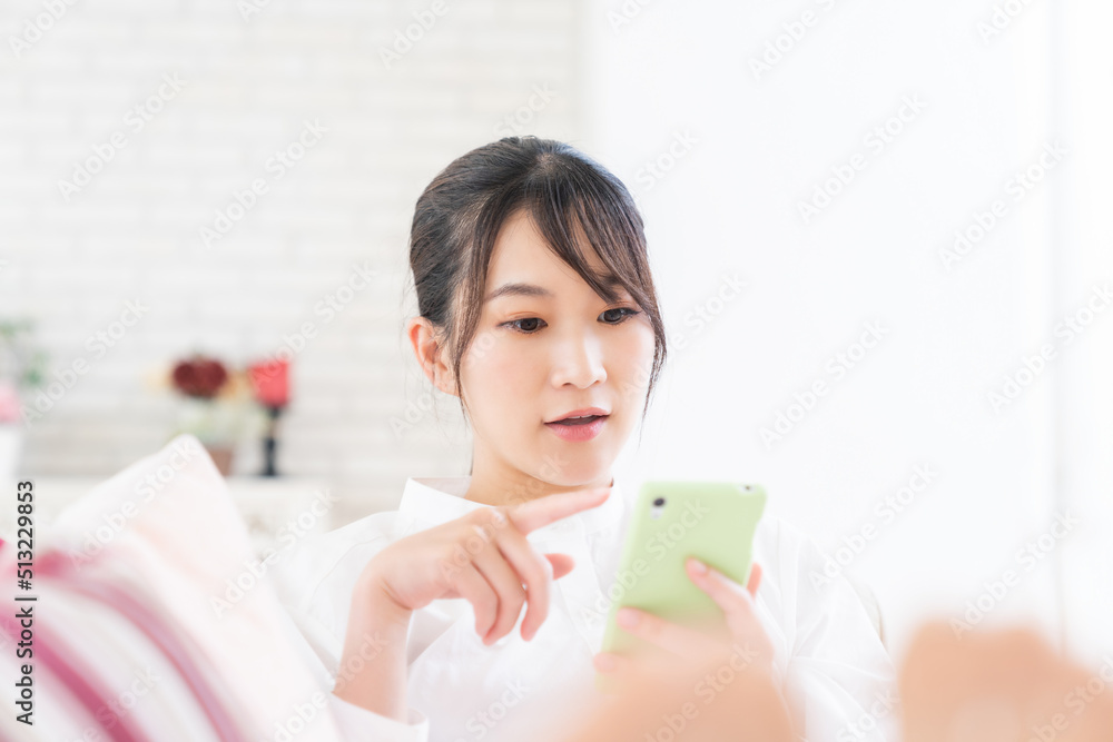 部屋でスマホを見る女性 部屋でスマホを見る女性