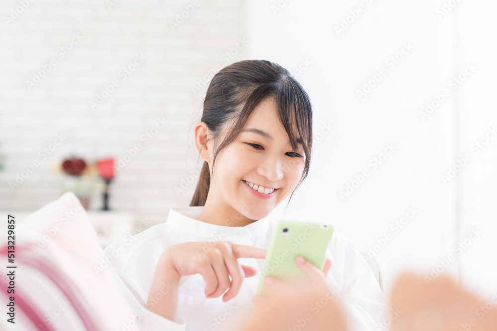 部屋でスマホを見る女性