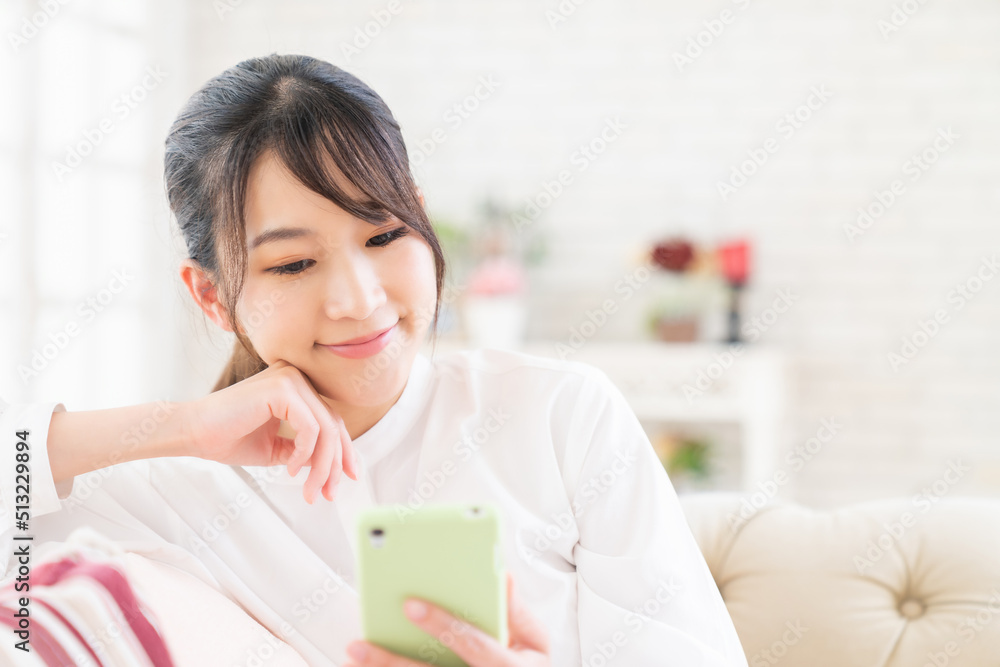 部屋でスマホを見る女性