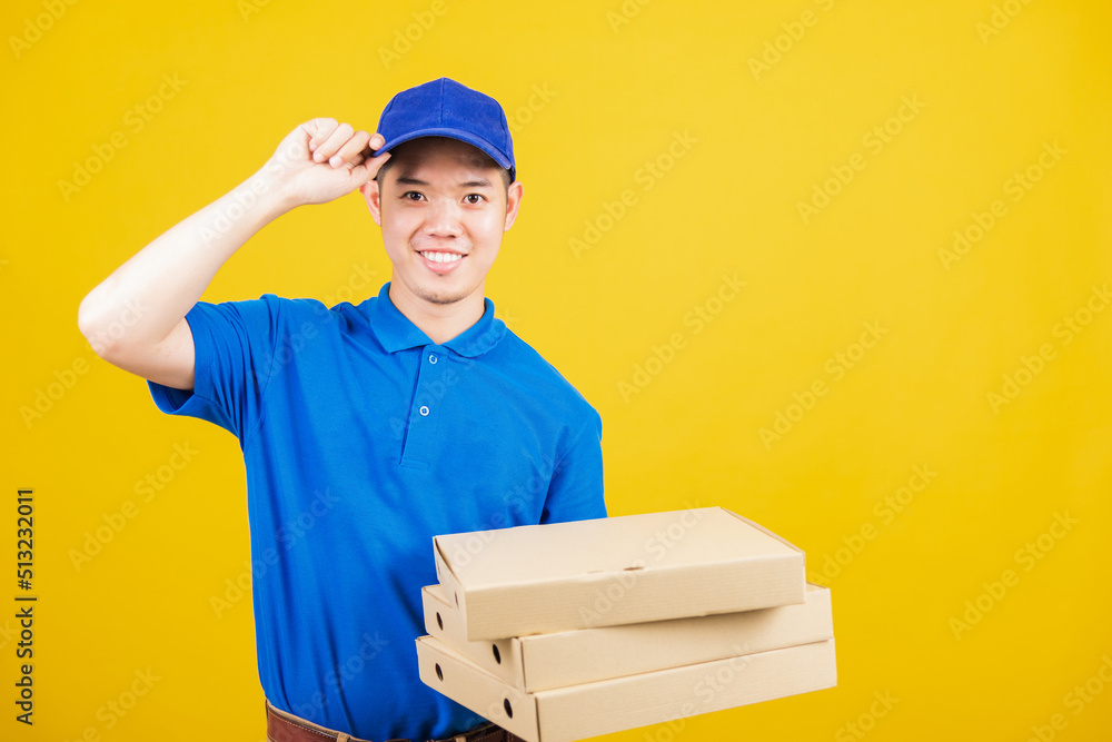 Portrait excited delivery service man standing he smile wearing blue t-shirt and cap uniform hold give food order pizza cardboard boxes looking to camera, studio shot isolated on yellow background Portrait excited delivery service man standing he smile wearing blue t-shirt and cap uniform hold give food order pizza cardboard boxes looking to camera, studio shot isolated on yellow background