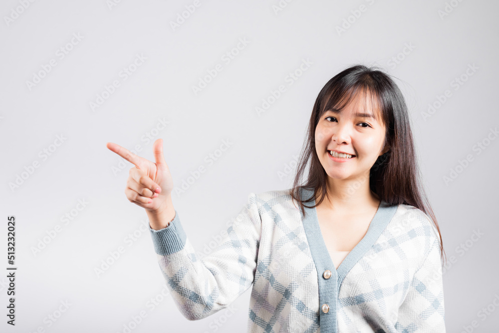 Smiling happy woman pointing finger out space, Portrait Asian beautiful young female point into empty looking to side away, studio shot isolated on white background with copy space Smiling happy woman pointing finger out space, Portrait Asian beautiful young female point into empty looking to side away, studio shot isolated on white background with copy space