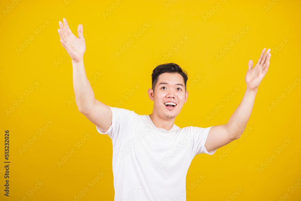 Asian handsome young man smile positive shaking hands enthusiastic shouting yes for win competition, male raising his fists Yes! with smiling delighted face, studio shot isolated on yellow background Asian handsome young man smile positive shaking hands enthusiastic shouting yes for win competition, male raising his fists Yes! with smiling delighted face, studio shot isolated on yellow background