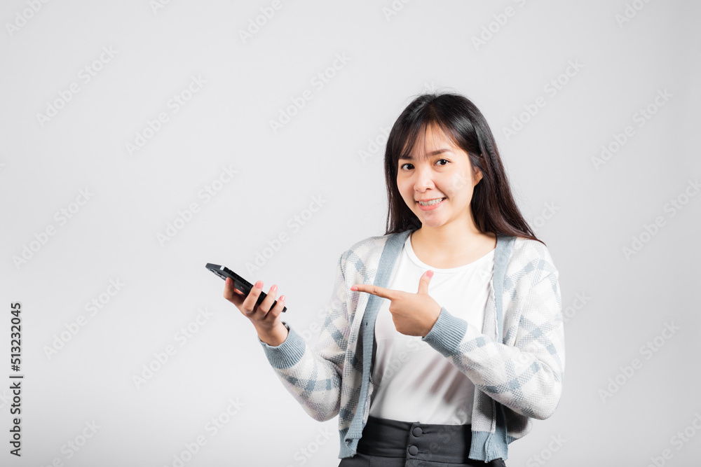 Woman excited celebrating win yes, great news on smartphone she pointing finger to mobile phone studio shot isolated white background, young female smiling having success after received promotion Woman excited celebrating win yes, great news on smartphone she pointing finger to mobile phone studio shot isolated white background, young female smiling having success after received promotion