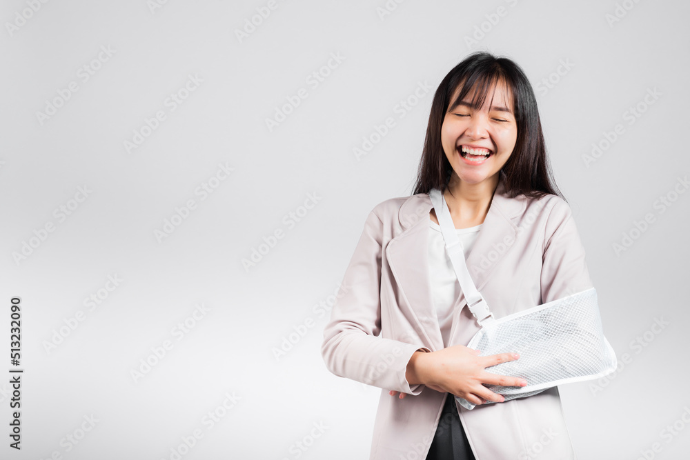Arm broken. Business woman confident smiling broken arm after accident and wear arm splint for treatment, excited happy Asian female sling support hand studio isolated on white background, copy space Arm broken. Business woman confident smiling broken arm after accident and wear arm splint for treatment, excited happy Asian female sling support hand studio isolated on white background, copy space