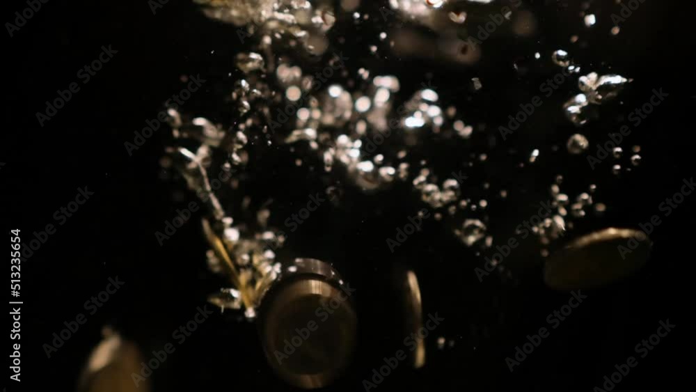 Currency coins fall in water on black background, slo mo. Metal money sinking in deep with shiny bubbles. Economic crisis concept. Currency coins fall in water on black background, slo mo. Metal money sinking in deep with shiny bubbles. Economic crisis concept.