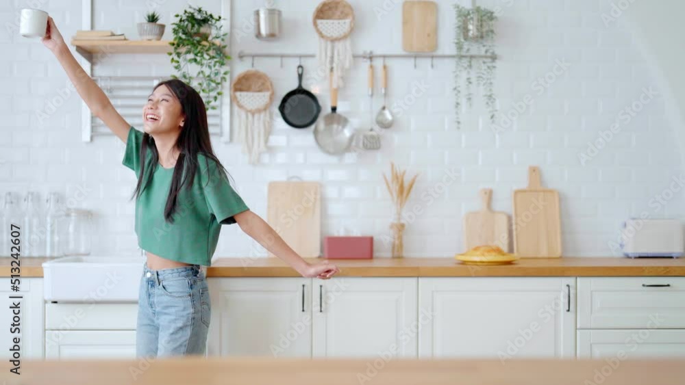 Asian young woman dancing in kitchen room. Female happy and relaxing at free time on weekend Asian young woman dancing in kitchen room. Female happy and relaxing at free time on weekend