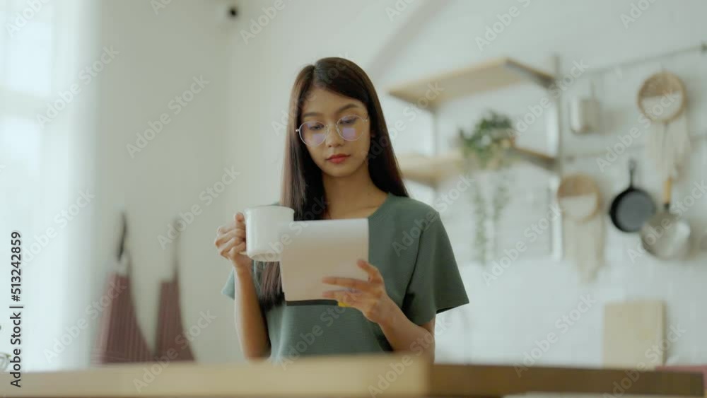 Happy young asian woman wearing glasses in kitchen at home. Female concentrate reading note cooking Happy young asian woman wearing glasses in kitchen at home. Female concentrate reading note cooking