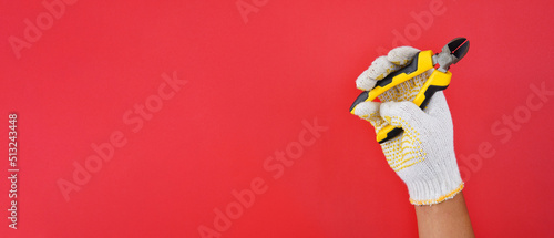 hand wearing white gloves holding diagonal pliers cutter isolated on a red background