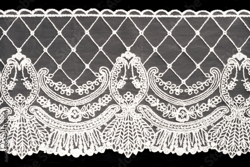 White lace on black background isolated horizontally. Macro