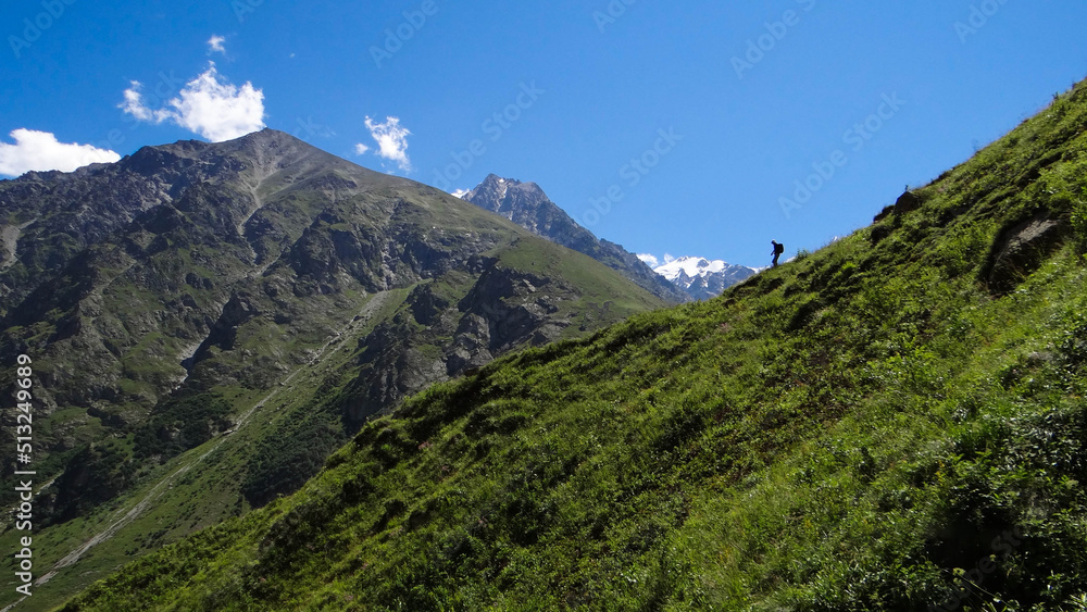 Obraz premium a tourist descends from the mountain along the trail.beautiful panorama of the mountains.