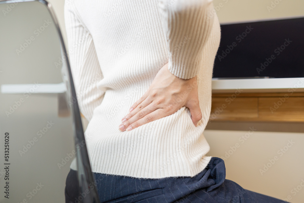 Body muscles stiff problem, asian young attractive woman, girl pain with back pain ache from computer work, holding massaging rubbing, hurt or sore while sitting on chair at home. Healthcare people.
