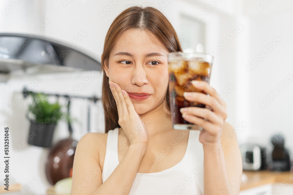 Health asian young woman touching her cheek, expression, suffering from toothache, decay or sensitivity cavity molar tooth or inflammation drink cold, sparkling water at home.Sensitive teeth people.