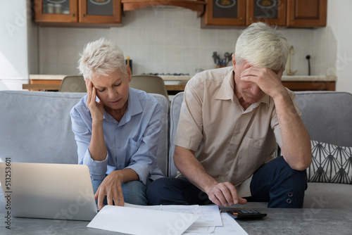 Older stressed unhappy wife and husband manage family finances feeling desperate due debts, unpaid bills, lack of money to pay monthly bills or bank mortgage. Financial crisis, bankruptcy concept photo