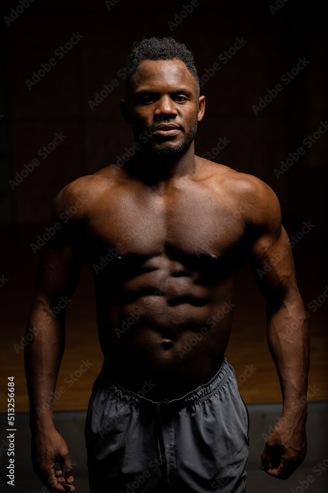 Portrait of an African American man with a naked torso in a dark studio. Muscular guy. Portrait of an African American man with a naked torso in a dark studio. Muscular guy.