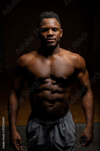 Portrait of an African American man with a naked torso in a dark studio. Muscular guy.