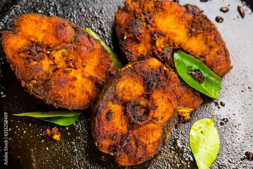 Fish fry on a frying pan with curry leaves. Close-up shot of Indian traditional Kerala style spicy fried fish.