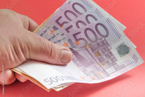 Euro banknotes in the hand. Red background