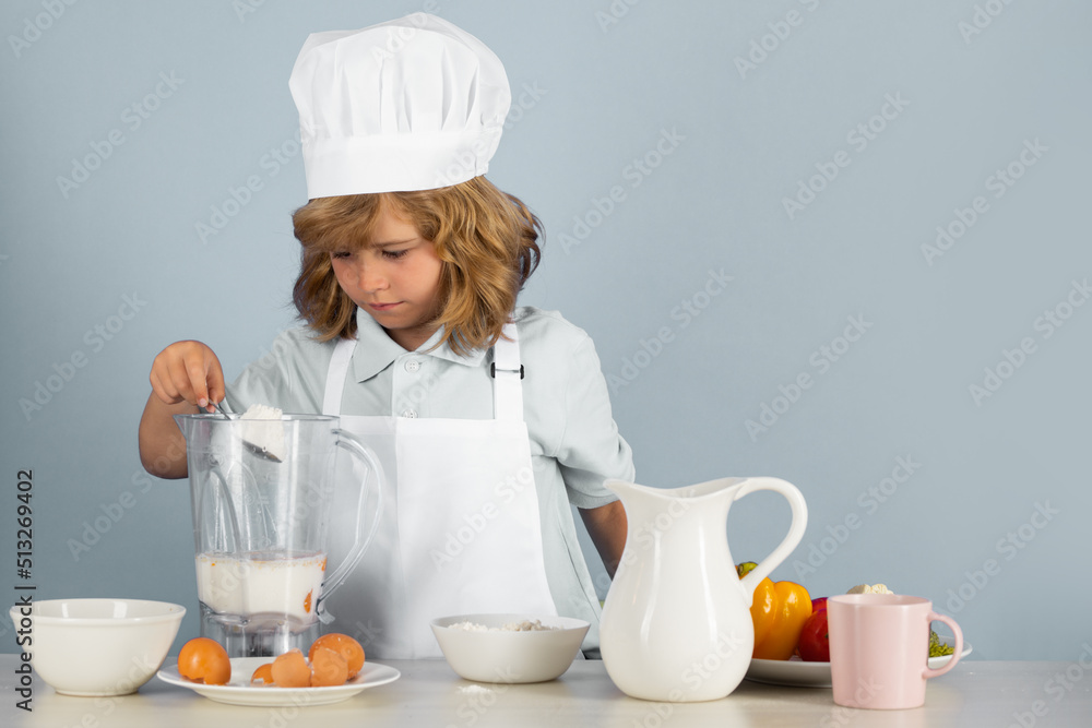 Child chef isolated on blue. Funny little kid chef cook wearing uniform cook cap and apron cooked food with flour in the kitchen. Child chef isolated on blue. Funny little kid chef cook wearing uniform cook cap and apron cooked food with flour in the kitchen.