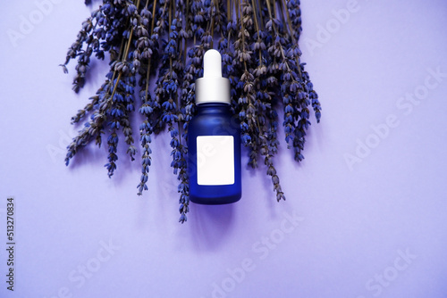 blue Lavender flower and a drop bottle composition on purple background. organic and Herbal Cosmetic concept background. Spa, organic oil, herbal essence, beauty  and life lifestyle.  photo