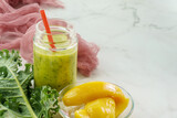 Mango kale smoothie on marble background in natural light with copy space