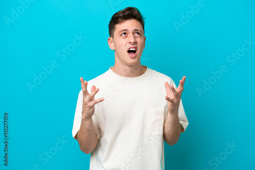 Young handsome Brazilian man isolated on blue background stressed overwhelmed photo