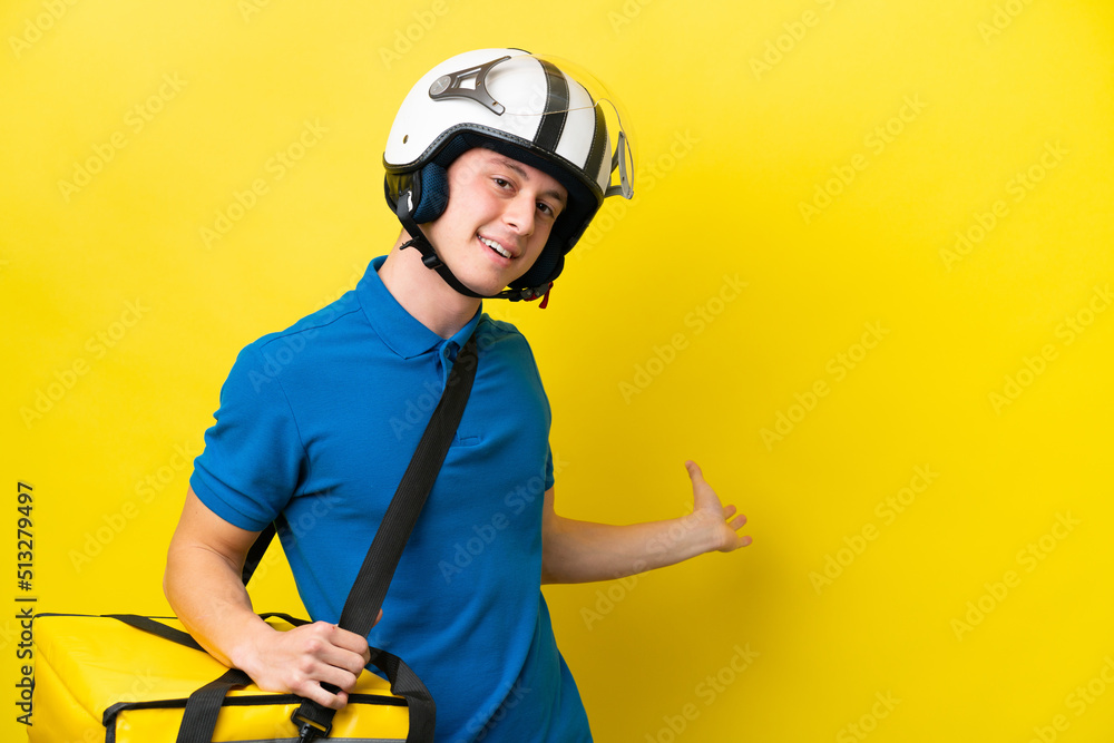 Young Brazilian man with thermal backpack isolated on yellow background extending hands to the side for inviting to come Young Brazilian man with thermal backpack isolated on yellow background extending hands to the side for inviting to come