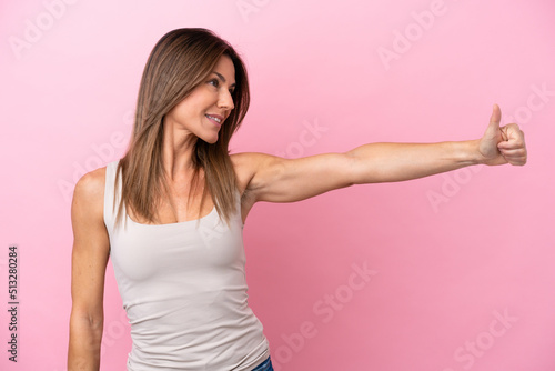 Middle age caucasian woman isolated on pink background giving a thumbs up gesture